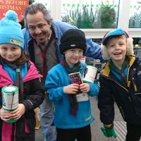 Three Beaver scouts fundraising with their leader.